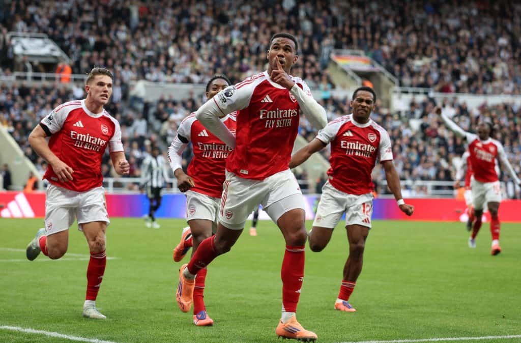Energetic Arsenal football players celebrating a goal during a match on the field.