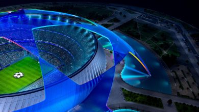 Colorful futuristic stadium illuminated at night, highlighting modern architecture and vibrant lighting.
