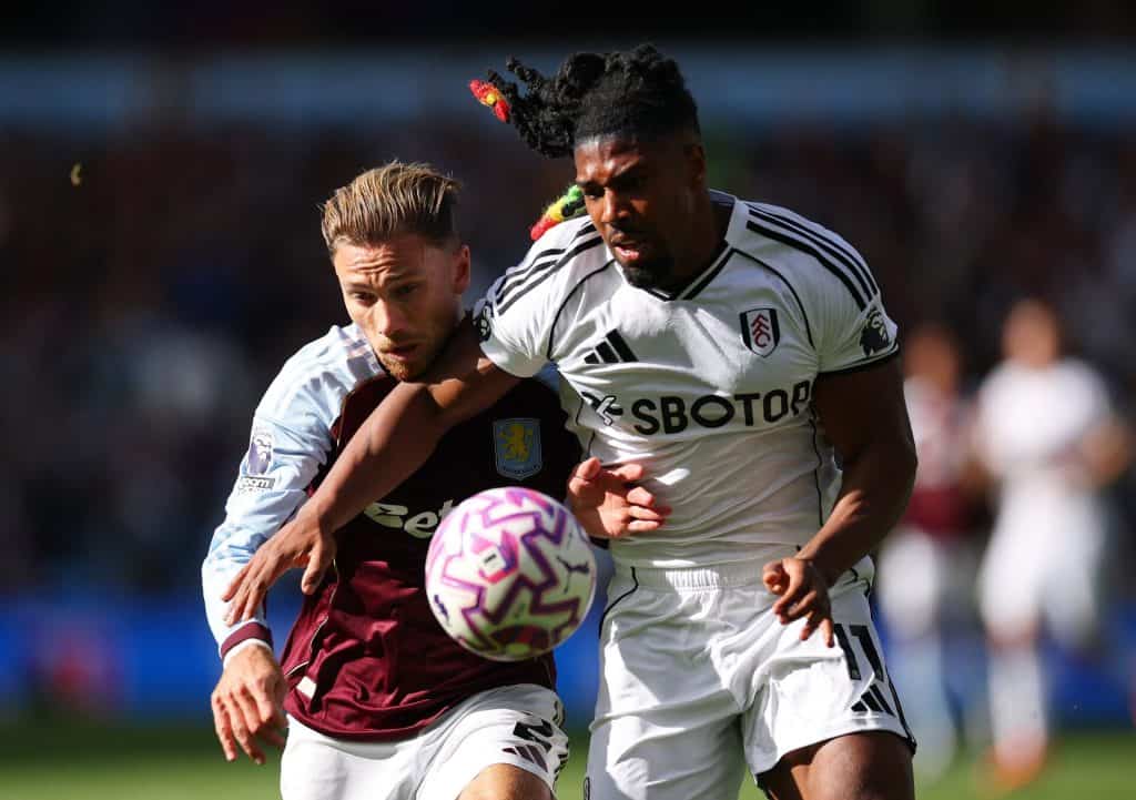 Intense football match featuring players from Aston Villa and Fulham competing fiercely for the ball during a daytime game. Action-packed moment showcasing athleticism and sportsmanship.