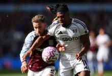 Intense football match featuring players from Aston Villa and Fulham competing fiercely for the ball during a daytime game. Action-packed moment showcasing athleticism and sportsmanship.