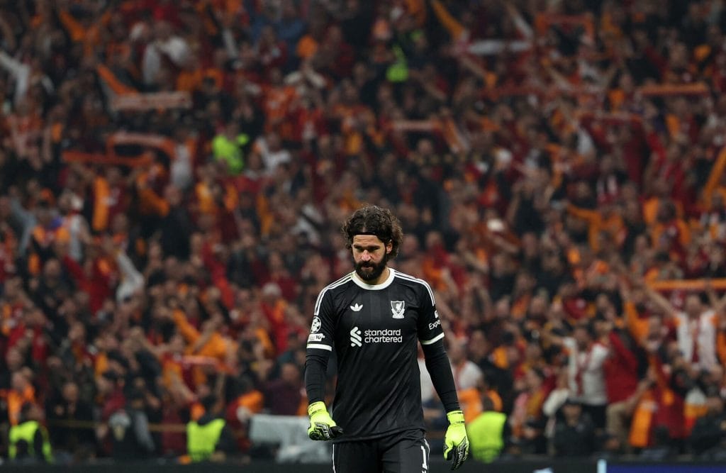 Excited soccer goalkeeper in black uniform with crowd in stadium background during match at ZareSport.et.