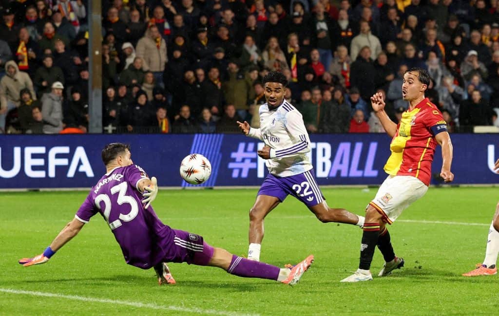 Dynamic soccer match action featuring players in colorful jerseys competing for the ball during a professional game at night.
