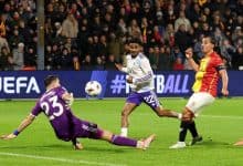 Dynamic soccer match action featuring players in colorful jerseys competing for the ball during a professional game at night.