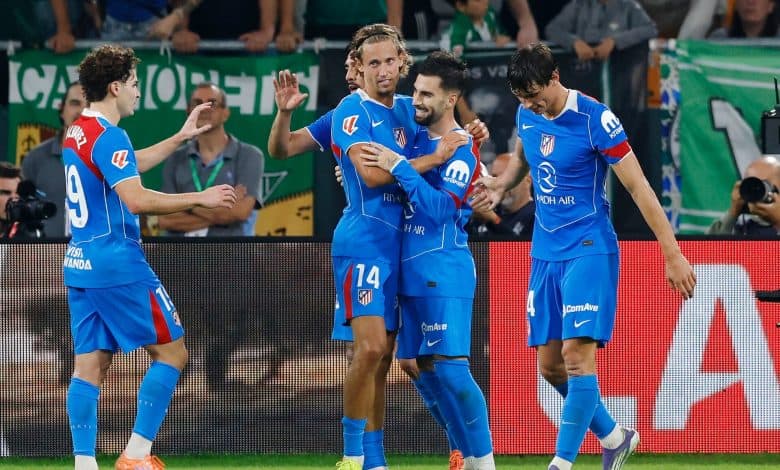 Vibrant soccer players celebrating a goal during an athletic match on the field, showcasing teamwork and sportsmanship, with a lively crowd in the background.