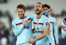 Vibrant football players celebrating a goal in West Ham United jerseys during a match.