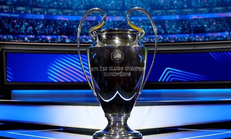 Shiny UEFA Champions League trophy on a presentation platform with a vibrant stadium background, celebrating European football success, iconic sports event trophy, ZareSport.et sports news.