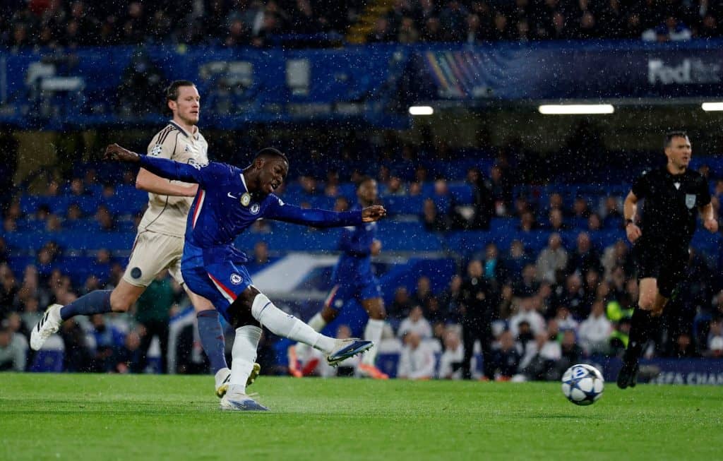 Rain-soaked soccer match featuring players from Chelsea FC and opposing team, intense action during a UEFA Champions League game at ZareSport.et.