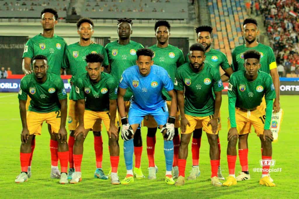 Ethiopia Finish with Pride in World Cup Qualifying Ethiopian national football team in green and yellow kits during a match, team members posed on the field, showcasing team spirit and competitiveness, vibrant stadium background.