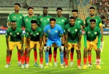 Ethiopian national football team in green and yellow kits during a match, team members posed on the field, showcasing team spirit and competitiveness, vibrant stadium background.