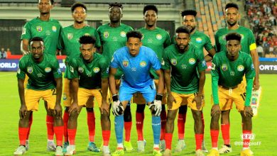 Ethiopian national football team in green and yellow kits during a match, team members posed on the field, showcasing team spirit and competitiveness, vibrant stadium background.