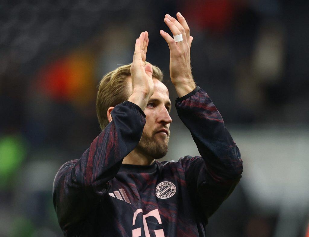 Harry Kane’s Bayern Love Story: Why He Might Never Come Back Energetic football player clapping during match, wearing Bayern Munich jersey, celebrating teamwork and sportsmanship on the field.