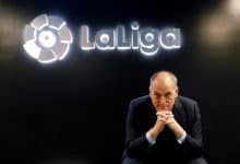 Professional man in formal suit sitting in front of La Liga logo at Zaresport.et sports website, promoting football, sports management, and La Liga partnerships.