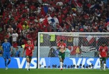 Vibrant soccer match between Iran and an opposing team, stadium filled with passionate fans waving flags, players displaying intense emotions during the game.
