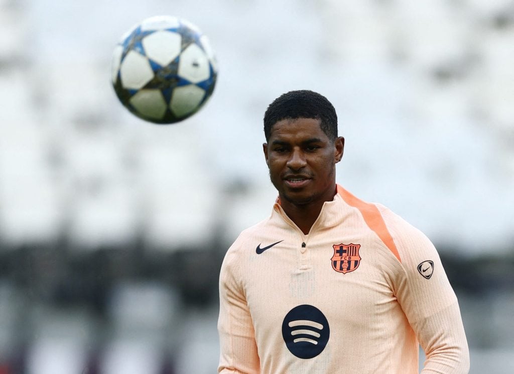 Young male soccer player in FC Barcelona training jersey during a practice session with a soccer ball in midair.