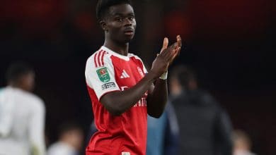 Fast football player celebrating on the field in a red and white jersey, team logo visible, during a match, sports action, athlete in motion, team sports, ZareSport.et focus.