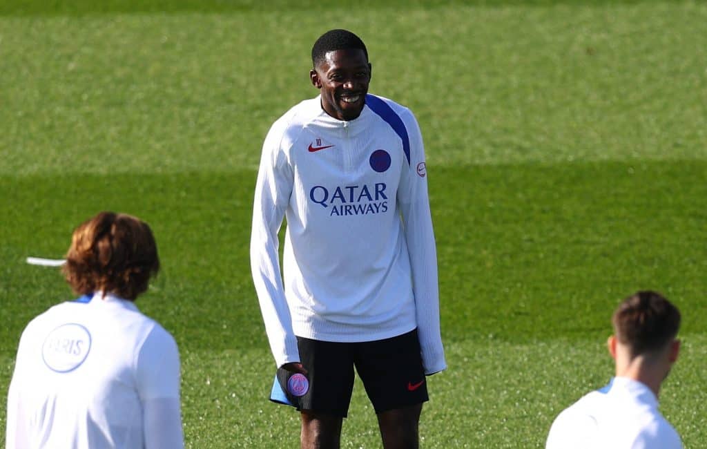 Young football player standing on the field in a white PSG jersey during training or warm-up.