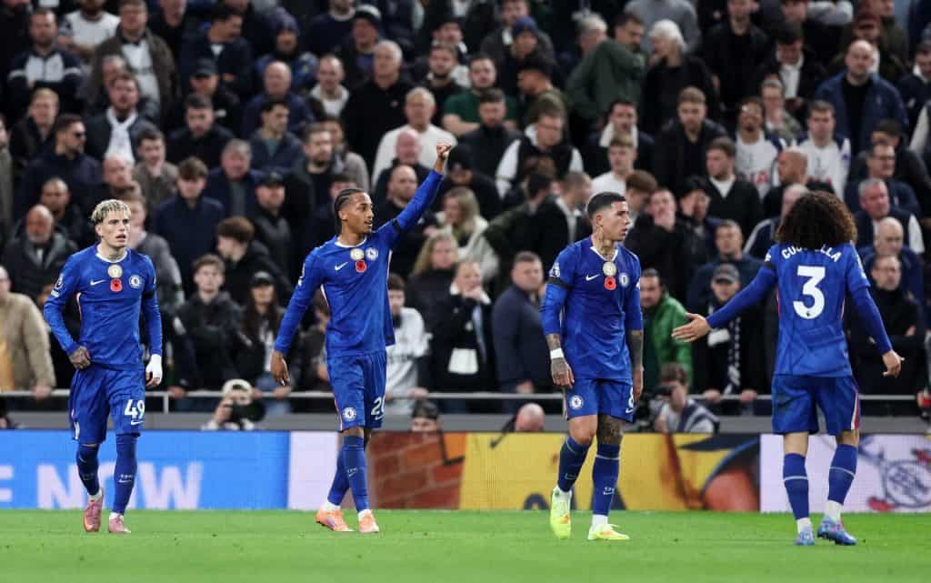 Cheering Chelsea Football Club players on the field during a match, with a packed stadium crowd in the background.