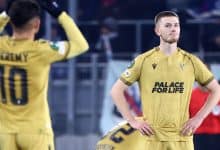 Soccer players wearing yellow uniforms on the field, one looking serious with hands on hips and the other adjusting their jersey, emphasizing sportsmanship and team spirit.