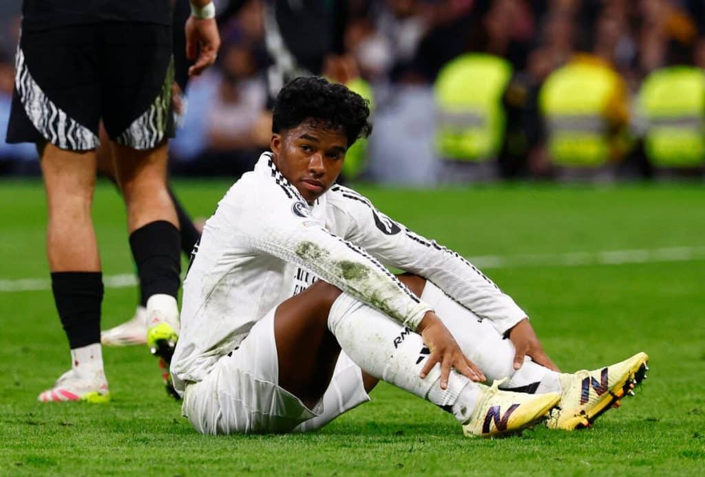 Young soccer player sitting on the field with muddy uniform after game injury, showcasing athleticism and teamwork.