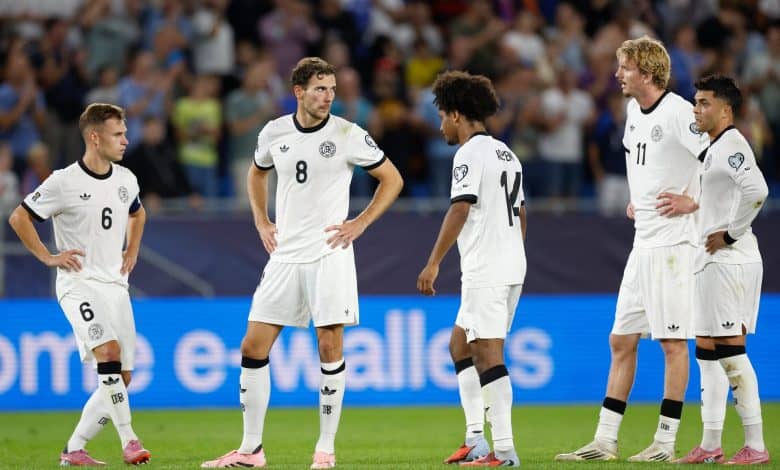 Young soccer players in white jerseys on the field during a match, team strategizing and discussing game tactics in front of a crowd.
