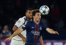 An intense soccer match featuring Paris Saint-Germain’s Kylian Mbappé heading the ball past an opponent during a UEFA Champions League game. Action-packed moment showcasing professional football skills.