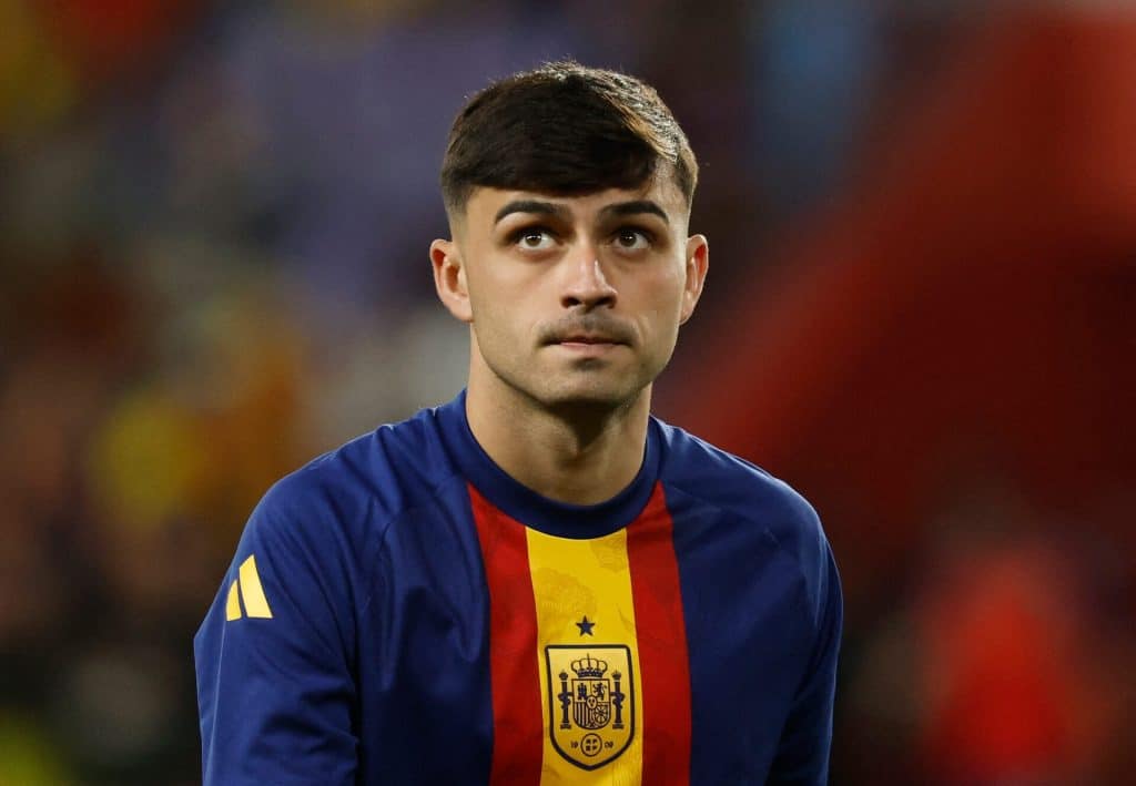Young male soccer player in Spain national team jersey, focusing during match.