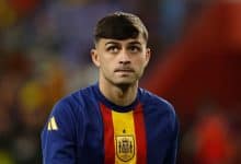 Young male soccer player in Spain national team jersey, focusing during match.