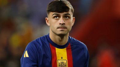 Young male soccer player in Spain national team jersey, focusing during match.