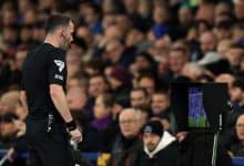 Flag of the referee with the laptop screen showing the match in the background.