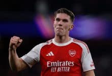 Professional Arsenal football player celebrating with fist pump during match, wearing red and white jersey, dynamic sports action, stadium background, sportswear, athletes, football, soccer, team sports, ZareSport.et relevancy.