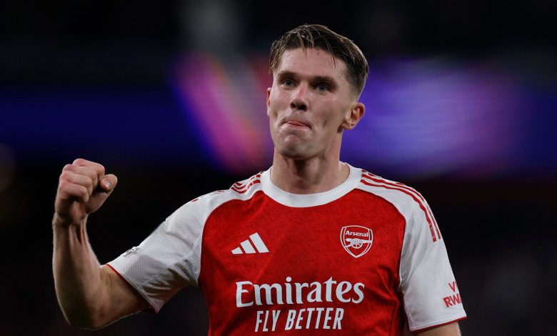 Professional Arsenal football player celebrating with fist pump during match, wearing red and white jersey, dynamic sports action, stadium background, sportswear, athletes, football, soccer, team sports, ZareSport.et relevancy.