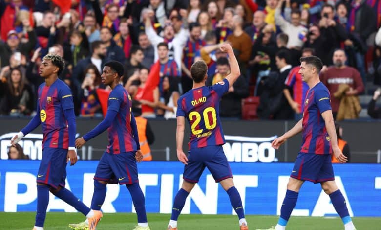 Brightly colored soccer players in action on the pitch with enthusiastic crowd cheering in the background.