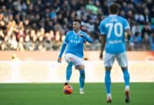 Athletic soccer player in blue uniform controlling the ball during a match with a large crowd watching, showcasing sportsmanship and competitive spirit.
