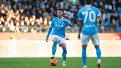 Athletic soccer player in blue uniform controlling the ball during a match with a large crowd watching, showcasing sportsmanship and competitive spirit.