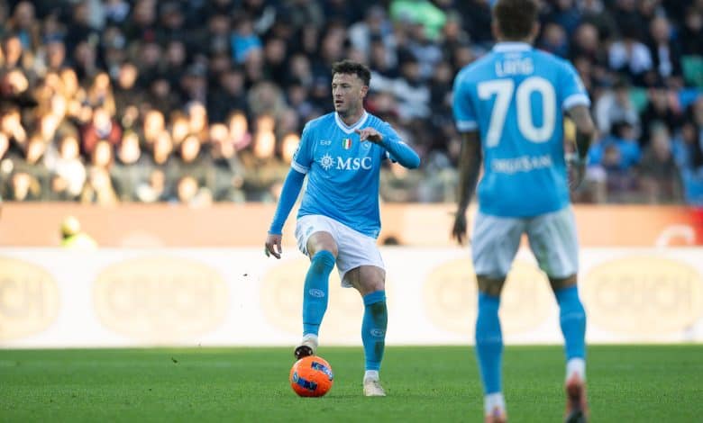 Athletic soccer player in blue uniform controlling the ball during a match with a large crowd watching, showcasing sportsmanship and competitive spirit.