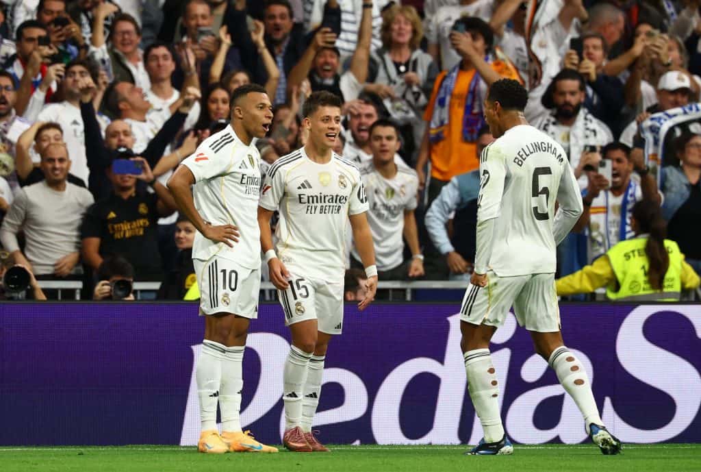 Real Madrid football team celebrating a goal with fans cheering in the stadium.