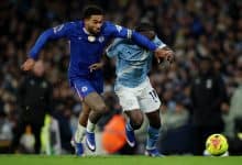A Chelsea player and a Manchester City player compete fiercely for control of the ball during a high-intensity soccer game.