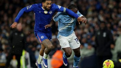A Chelsea player and a Manchester City player compete fiercely for control of the ball during a high-intensity soccer game.