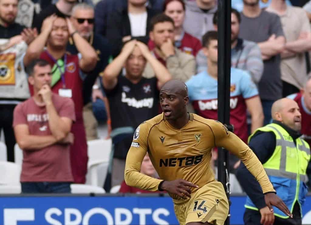 Vibrant action shot of a professional soccer player in golden jersey during a match, with an attentive crowd in the background capturing the intensity and excitement of the game.