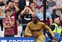 Vibrant action shot of a professional soccer player in golden jersey during a match, with an attentive crowd in the background capturing the intensity and excitement of the game.