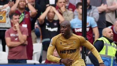 Vibrant action shot of a professional soccer player in golden jersey during a match, with an attentive crowd in the background capturing the intensity and excitement of the game.