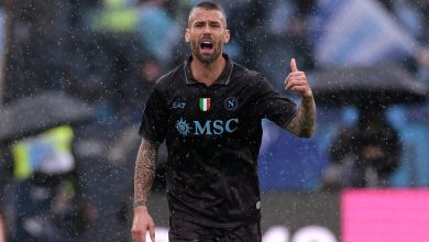 High-action shot of a footballer celebrating on the field during a rainy match, showcasing passion and athleticism, with fans in the background.