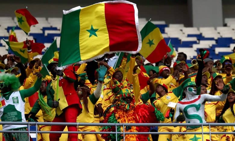 Senegal football fans waving flags, dressed in yellow, green, and red, rally together for their team at a stadium, embodying passion, patriotism, and team spirit.