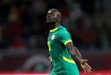 Athletic soccer player celebrating on the field during a match, wearing a green and yellow jersey representing Senegal national team, in a dynamic action shot.
