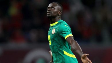 Athletic soccer player celebrating on the field during a match, wearing a green and yellow jersey representing Senegal national team, in a dynamic action shot.