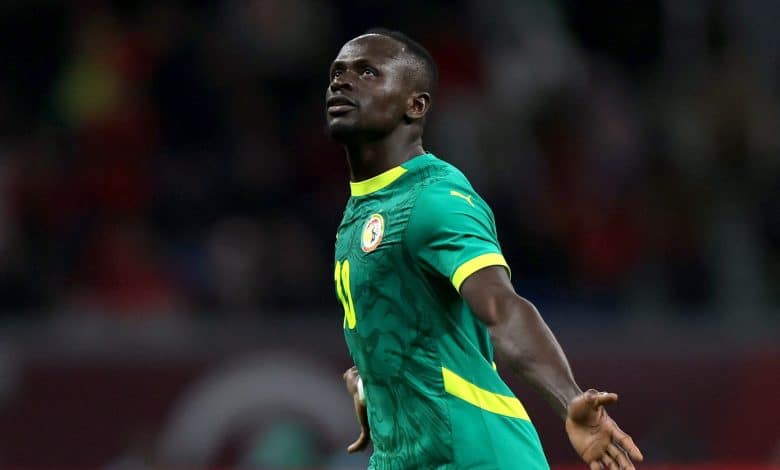 Athletic soccer player celebrating on the field during a match, wearing a green and yellow jersey representing Senegal national team, in a dynamic action shot.