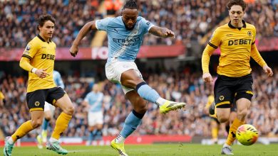 Male soccer players competing during a match, wearing team jerseys, focusing on the ball and showcasing athletic skills on the field.