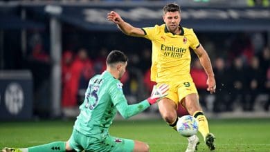 Player in yellow jersey kicking ball past goalkeeper in green kit.