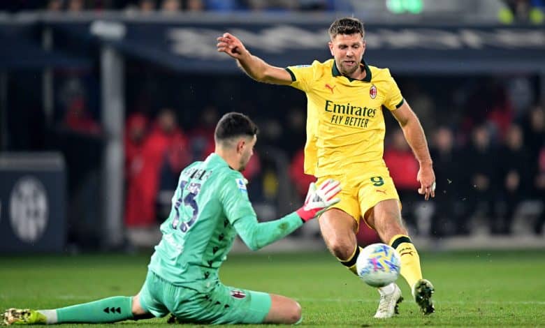 Player in yellow jersey kicking ball past goalkeeper in green kit.