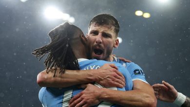 Two football players embracing in celebration after scoring, under stadium lights, during a match.